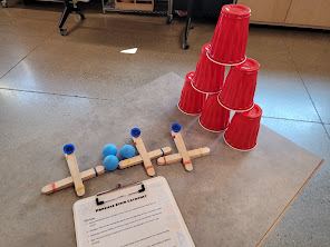 Craft-stick catapults with foam balls aimed at a stack of red cups