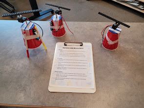 Three red-cup builds with propellers next to a clipboard of instructions