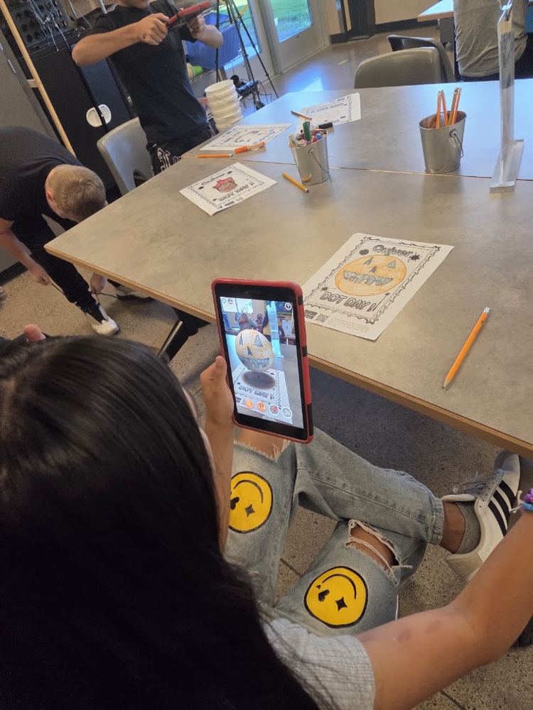 Student using a tablet to see a coloring page turn into a 3D augmented reality pumpkin