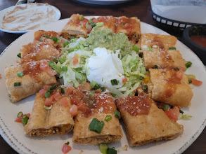 A plate of Mexican food topped with guacamole and sour cream