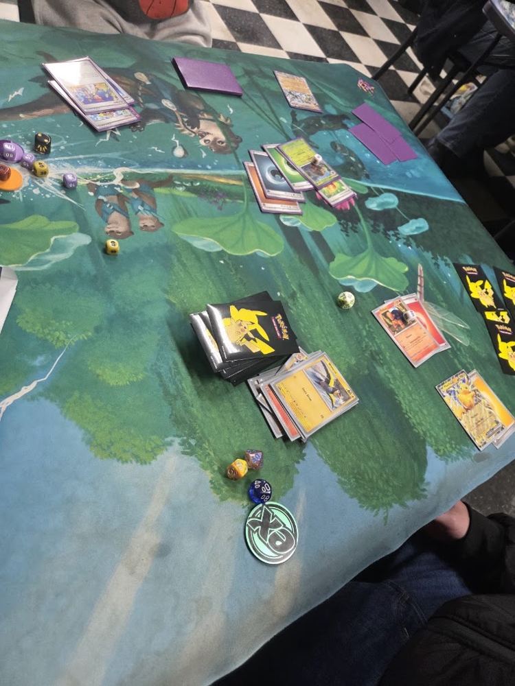 Pokémon trading cards and dice laid out on a play mat