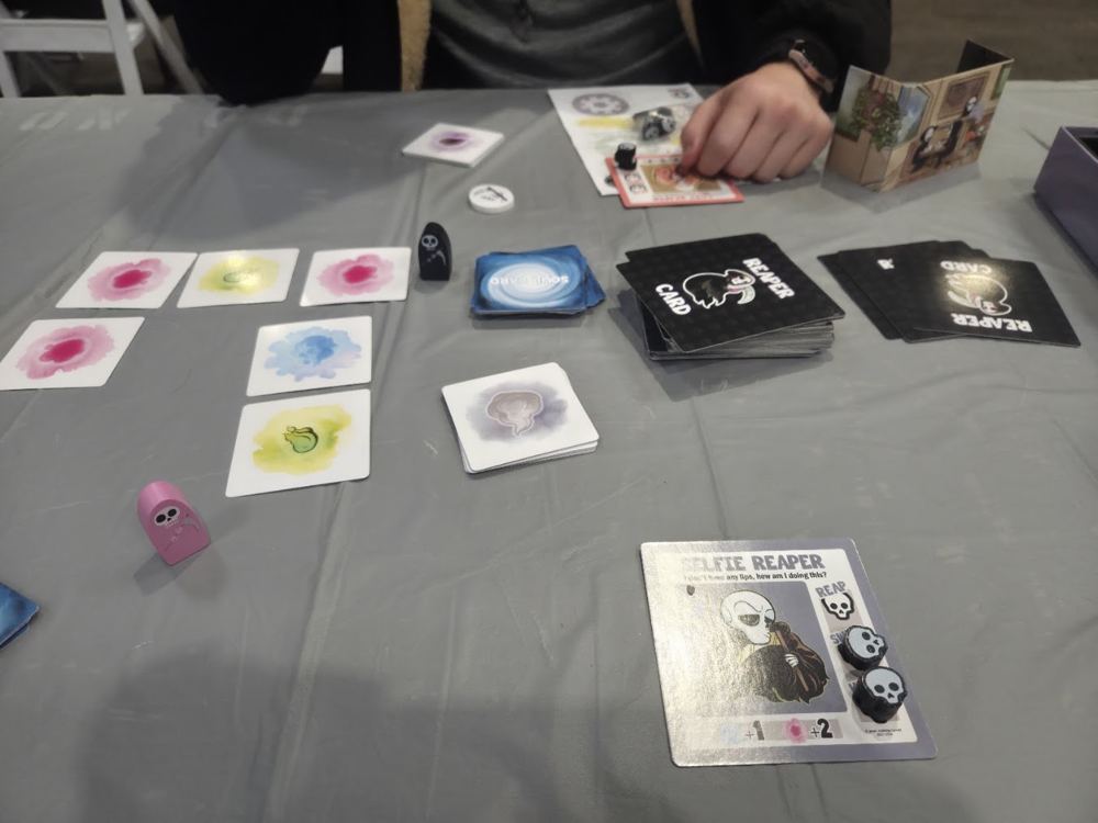A card game with reaper cards and soul cards on a gray table