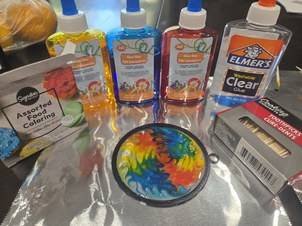 A swirly rainbow suncatcher made from colored glue in a round frame
